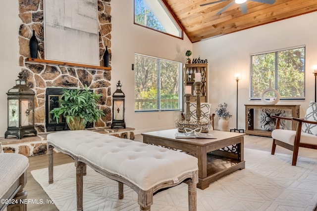 living area with high vaulted ceiling, ceiling fan, a fireplace, and wood ceiling