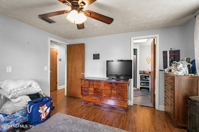 bedroom featuring ceiling fan, dark wood-type flooring, and a textured ceiling