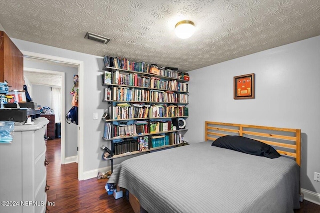 bedroom with a textured ceiling and dark hardwood / wood-style floors