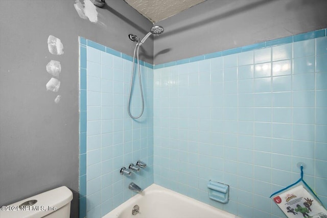 bathroom with tiled shower / bath combo and toilet