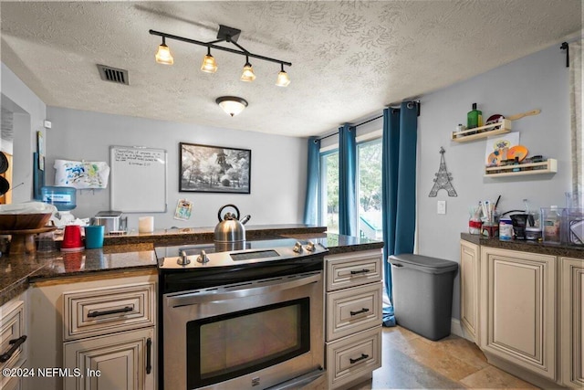 kitchen featuring cream cabinetry, a textured ceiling, rail lighting, and electric stove