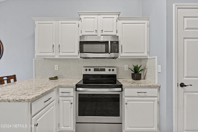 kitchen with decorative backsplash, a kitchen breakfast bar, stainless steel appliances, and white cabinetry