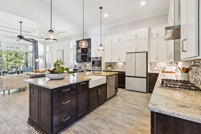 kitchen with appliances with stainless steel finishes, a kitchen island with sink, sink, pendant lighting, and white cabinetry