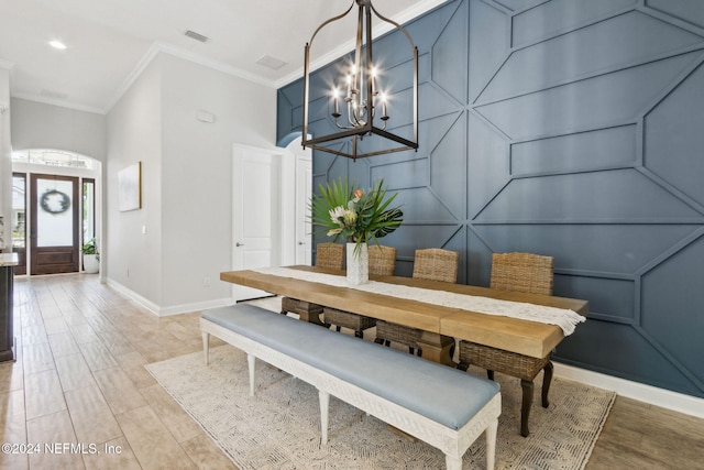 dining space featuring light hardwood / wood-style floors, crown molding, and a chandelier