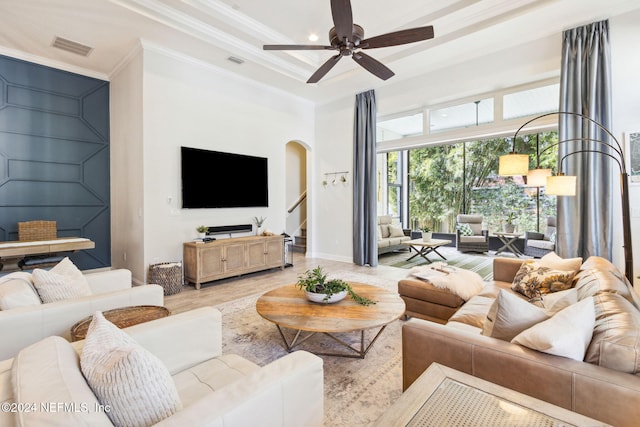 living room featuring built in features, light hardwood / wood-style flooring, ceiling fan, and ornamental molding