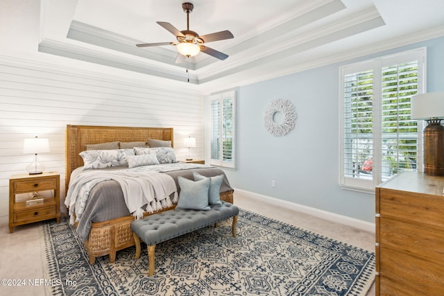 carpeted bedroom featuring a raised ceiling, ceiling fan, and ornamental molding