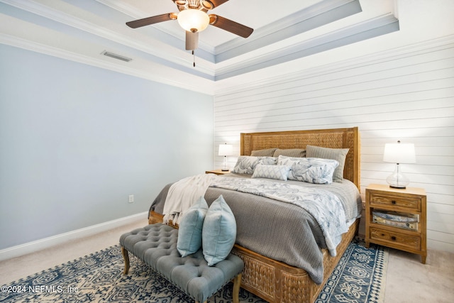 carpeted bedroom with a raised ceiling, ceiling fan, and ornamental molding