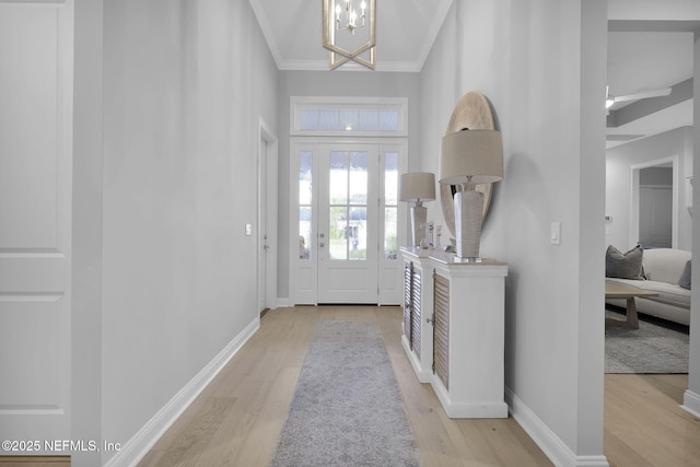 entryway with crown molding, light wood-type flooring, a high ceiling, and an inviting chandelier