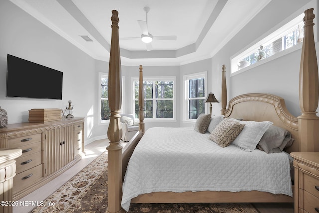 bedroom featuring ceiling fan, ornamental molding, and a tray ceiling