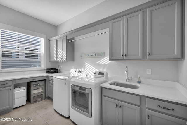 clothes washing area featuring sink, washer and clothes dryer, light tile patterned floors, and cabinets