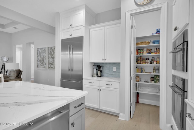 kitchen with light hardwood / wood-style flooring, white cabinets, light stone counters, decorative backsplash, and built in fridge