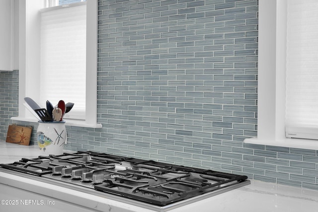 interior details with light stone countertops, gas stovetop, and backsplash