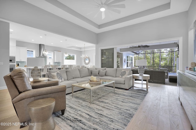 living room with plenty of natural light, a raised ceiling, and light wood-type flooring