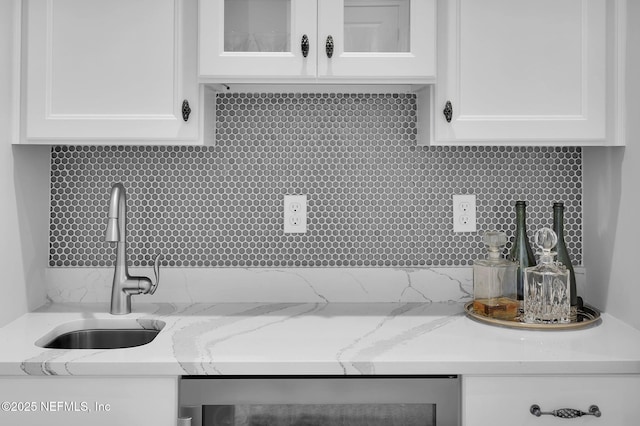 kitchen with sink, white cabinets, tasteful backsplash, and light stone countertops