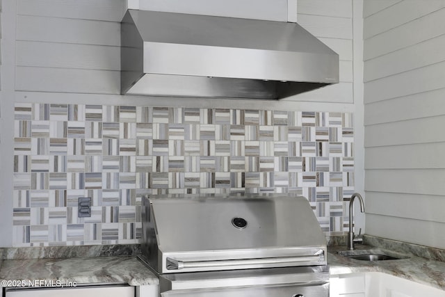 details with sink, wooden walls, wall chimney range hood, and stone counters