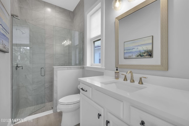 bathroom featuring a shower with shower door, hardwood / wood-style flooring, toilet, and vanity