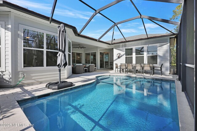 view of pool with outdoor lounge area, ceiling fan, a patio, and a lanai