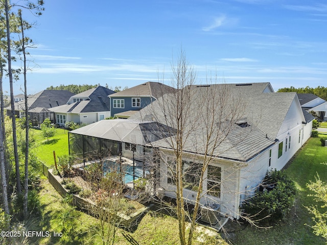 rear view of house featuring glass enclosure and a yard