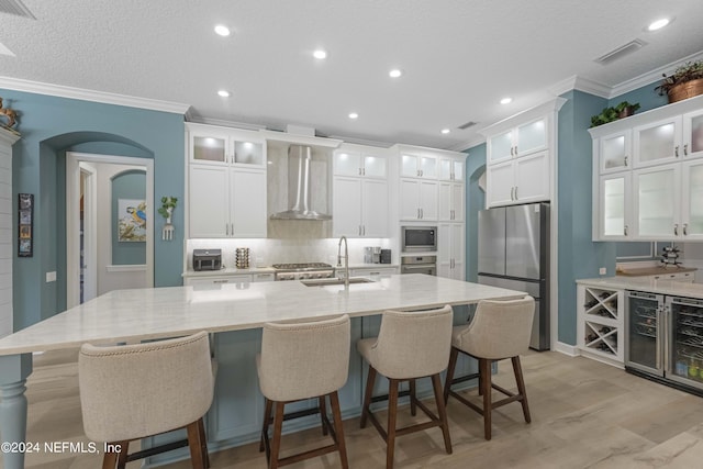 101 Montura Dr, Ponte Vedra Beach, FL 32082 - kitchen with appliances with stainless steel finishes, wall chimney range hood, ornamental molding, a spacious island, and white cabinetry