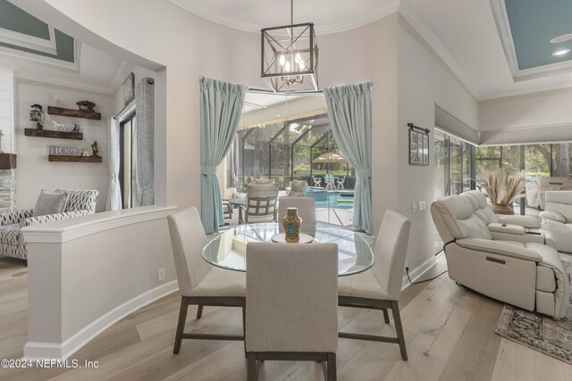 dining space with plenty of natural light, light hardwood / wood-style floors, ornamental molding, and a chandelier