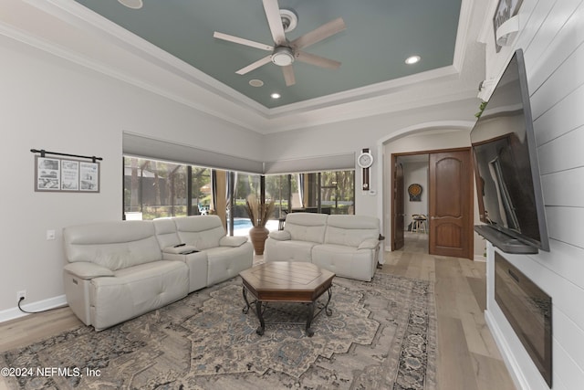 living room with a tray ceiling, light hardwood / wood-style flooring, ceiling fan, and ornamental molding