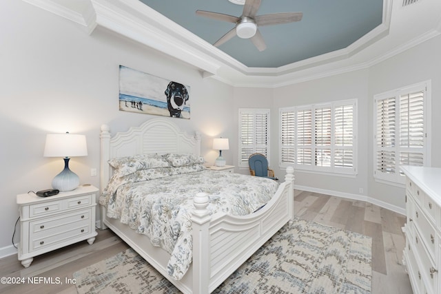 bedroom featuring a raised ceiling, ceiling fan, light hardwood / wood-style flooring, and ornamental molding