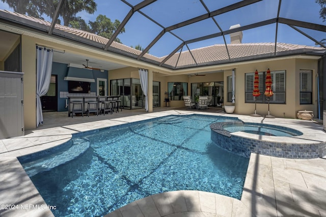 view of pool with glass enclosure, an outdoor bar, ceiling fan, an in ground hot tub, and a patio