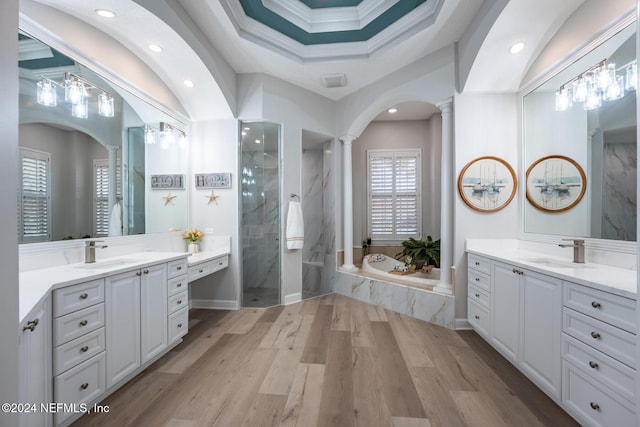 bathroom featuring decorative columns, ornamental molding, vanity, separate shower and tub, and wood-type flooring