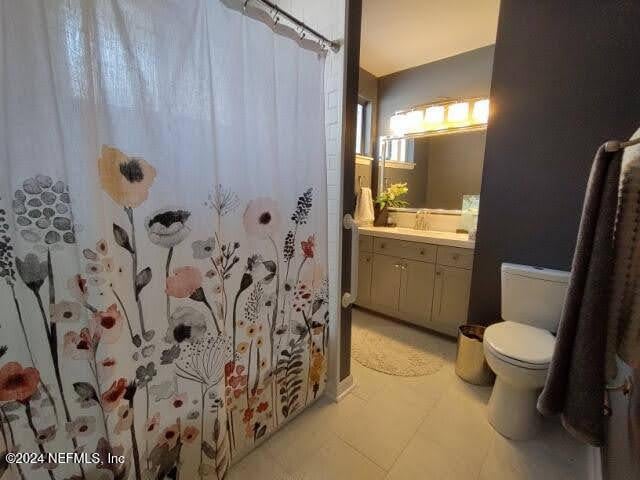 bathroom featuring tile patterned floors, walk in shower, vanity, and toilet