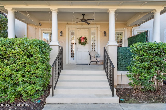 entrance to property with a porch, a ceiling fan, and stucco siding