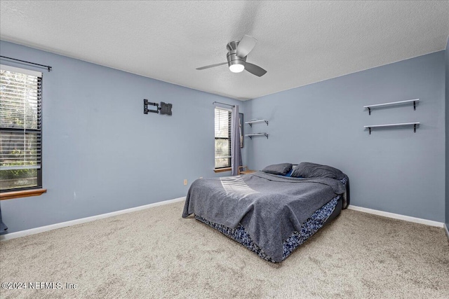 bedroom with carpet, ceiling fan, a textured ceiling, and multiple windows