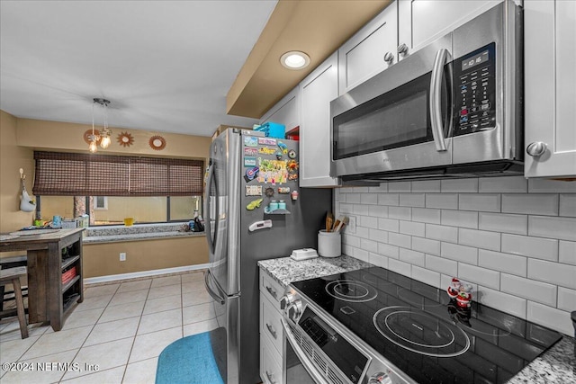 kitchen featuring white cabinets, light stone countertops, stainless steel appliances, and hanging light fixtures