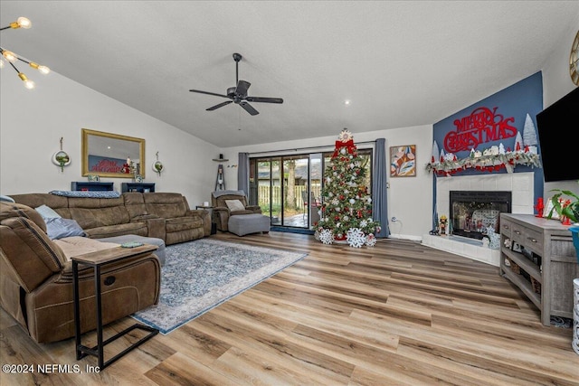 living room featuring hardwood / wood-style flooring, a textured ceiling, a fireplace, and vaulted ceiling