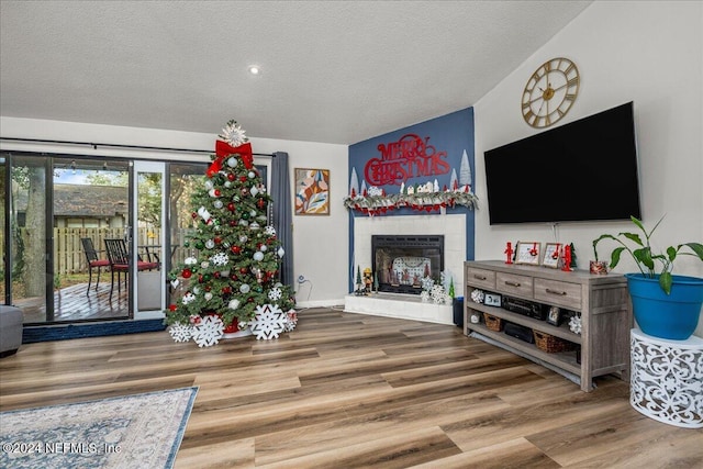 living room featuring a tile fireplace, a textured ceiling, and hardwood / wood-style flooring