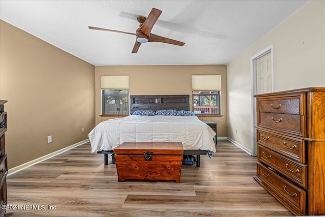 bedroom with hardwood / wood-style flooring, ceiling fan, and a textured ceiling