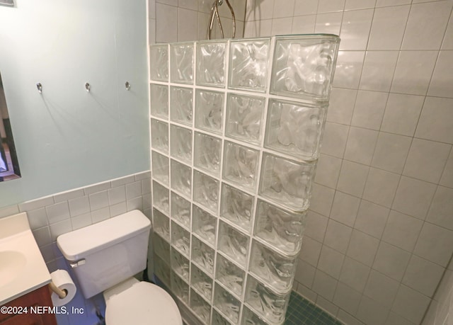 3145 Coastal Hwy Unit 1138, Saint Augustine, FL 32084 - bathroom featuring tiled shower, toilet, tile walls, and vanity