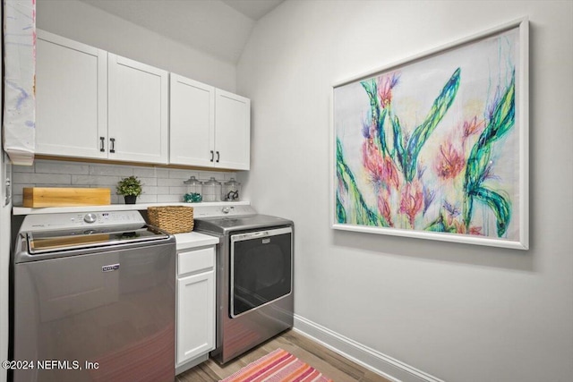 laundry room featuring washer and clothes dryer, cabinets, and hardwood / wood-style flooring