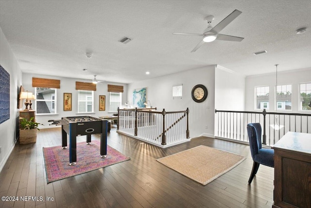 playroom with a textured ceiling, crown molding, dark hardwood / wood-style flooring, and ceiling fan with notable chandelier