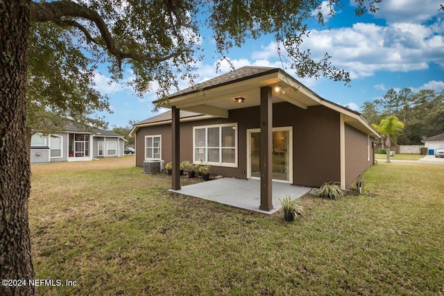 back of house with stucco siding, a lawn, and a patio