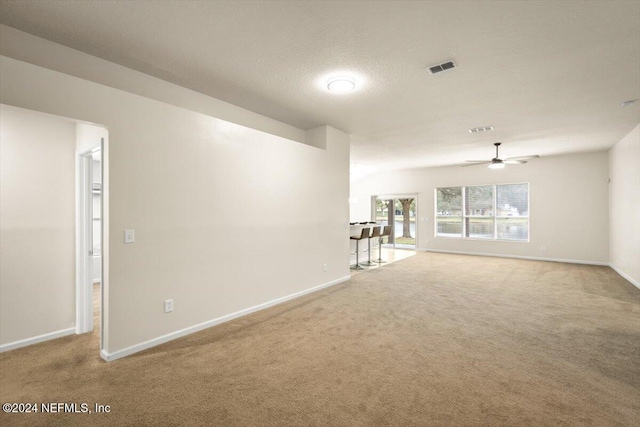 carpeted empty room with ceiling fan and a textured ceiling