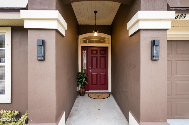 entrance to property with a garage and stucco siding