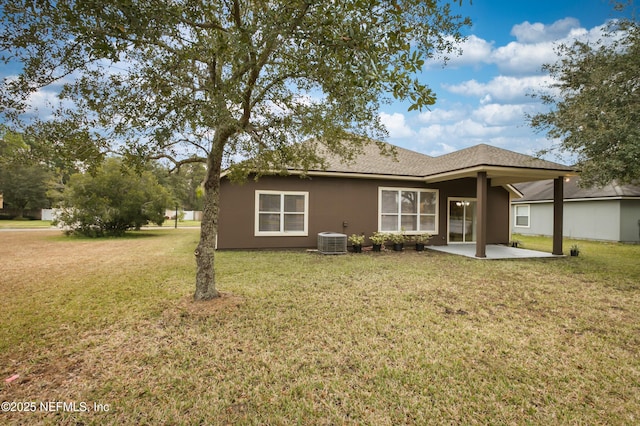 rear view of property with a yard, stucco siding, central AC, and a patio