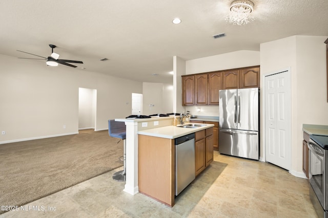 kitchen featuring visible vents, a kitchen island with sink, light countertops, appliances with stainless steel finishes, and open floor plan