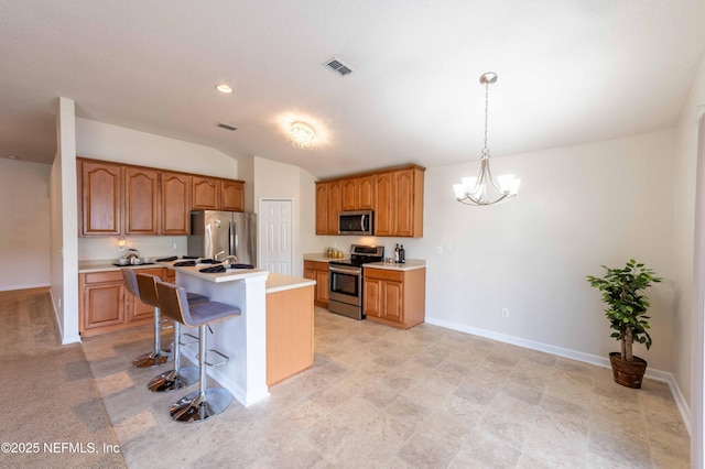 kitchen featuring visible vents, a kitchen breakfast bar, stainless steel appliances, and light countertops