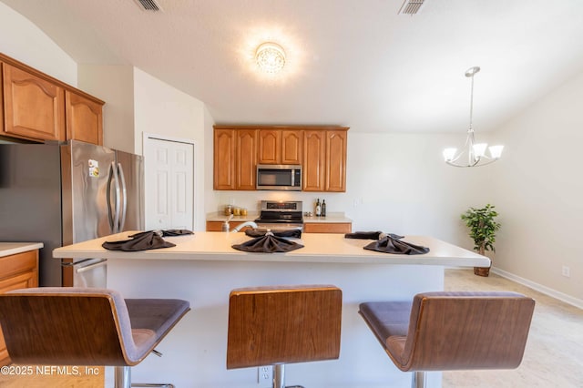 kitchen with stainless steel appliances, a kitchen bar, a chandelier, and light countertops