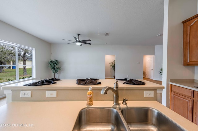 kitchen featuring brown cabinets, light countertops, and a sink