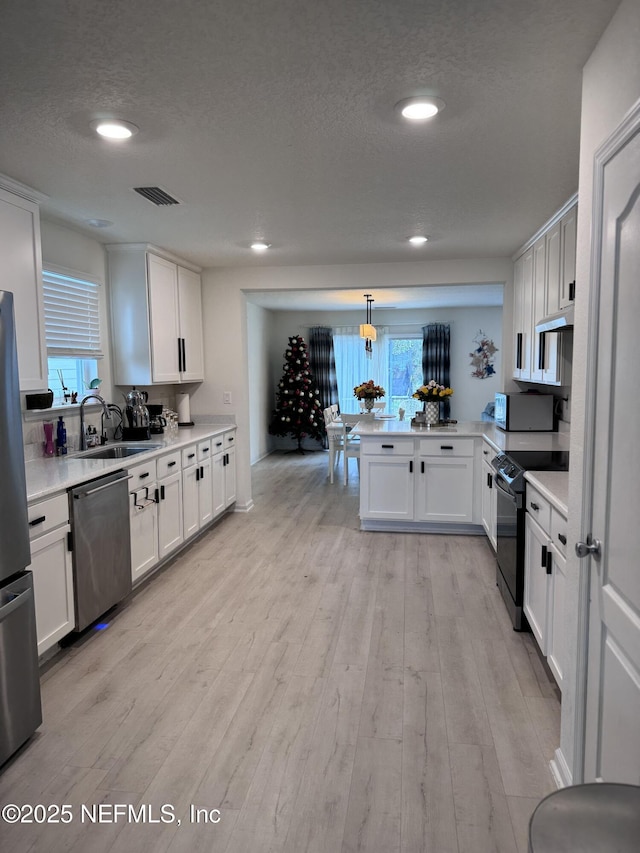 kitchen with kitchen peninsula, white cabinetry, and stainless steel appliances