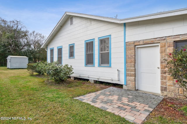 rear view of house with a patio area, a yard, and a shed