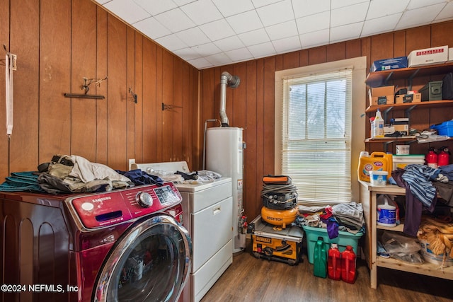 laundry area with hardwood / wood-style flooring, wood walls, gas water heater, and separate washer and dryer