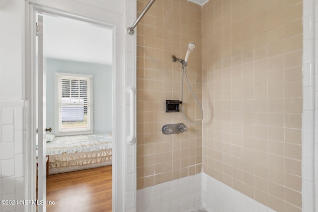 bathroom with tiled shower and hardwood / wood-style flooring